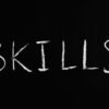Chalkboard with the word ‘skills’ written, emphasizing essential coaching skills.