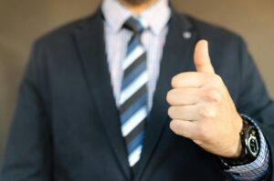 Close-up of a business professional giving a thumbs up, symbolizing confidence and success in career coaching