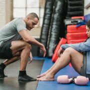 Health and wellness coach supporting a woman during a workout session, offering encouragement and mindset support in a gym setting.