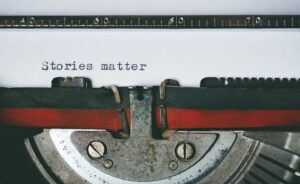 Close-up of a vintage typewriter with the words “Stories matter” typed on paper—symbolizing the power of storytelling in coaching and personal transformation.